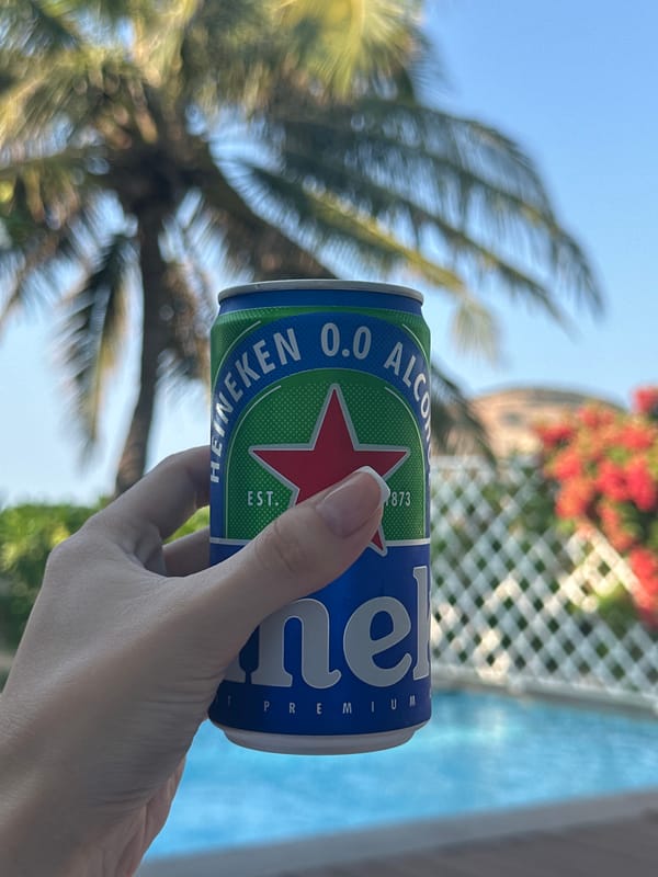 Non-alcoholic beer held at poolside location with tropical scenery