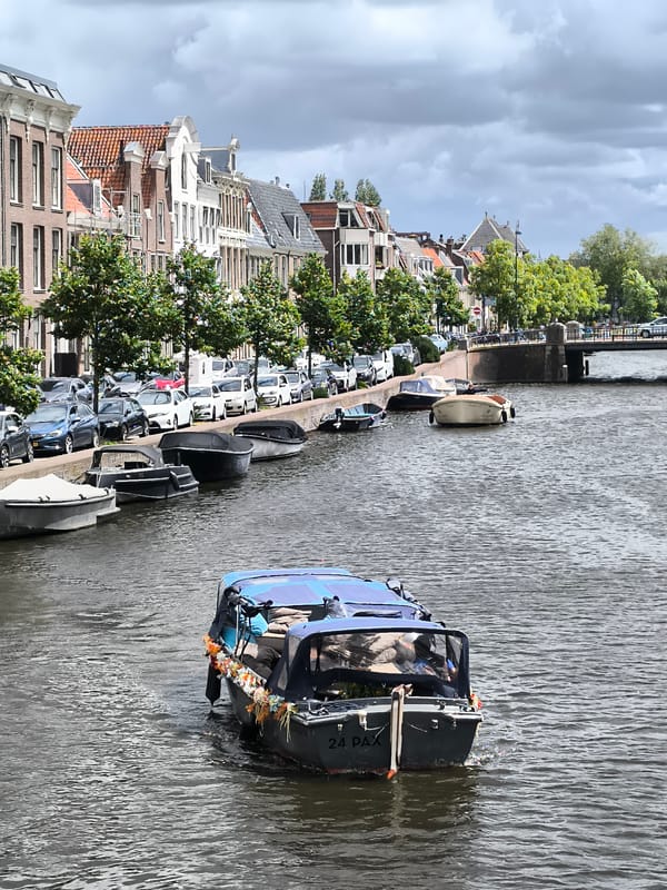 Boat travels through Haarlem canal past historic insurance building
