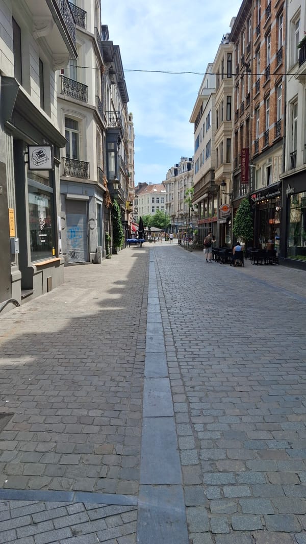 European city streets, transit stops, and storefronts on a summer afternoon