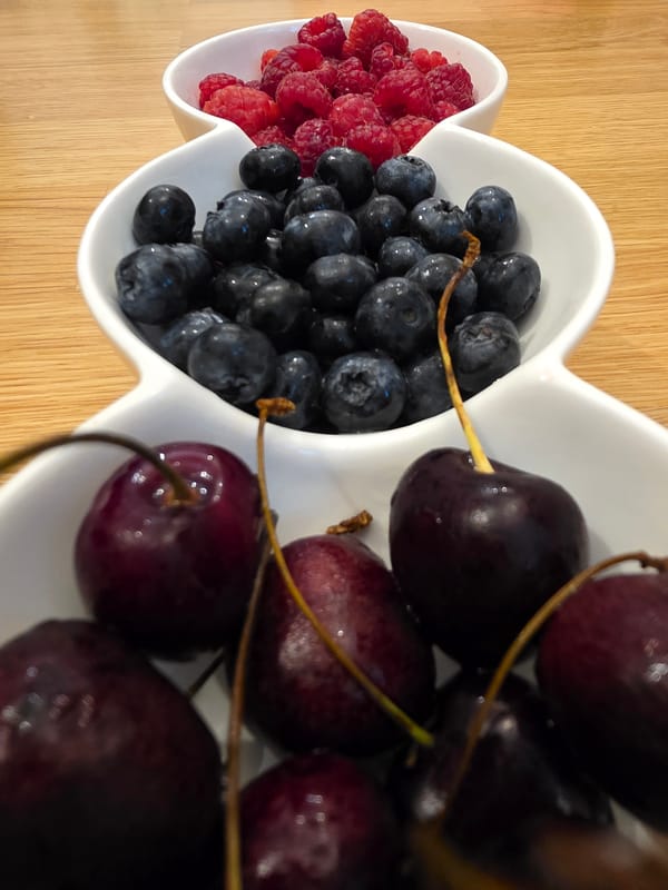 Fresh berries in ceramic bowls on a wooden surface