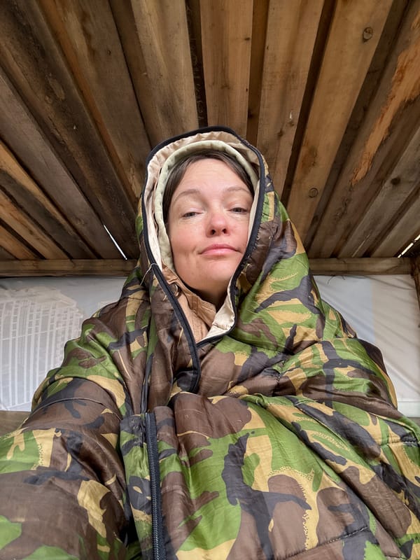 Person rests in makeshift wooden shelter in rural Russia