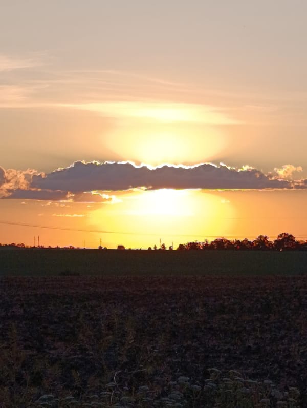 Vivid rural sunset with rays breaking through dark clouds