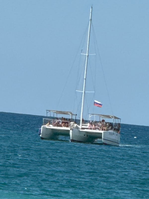 Sunny beach resort morning with café, loungers, and catamaran