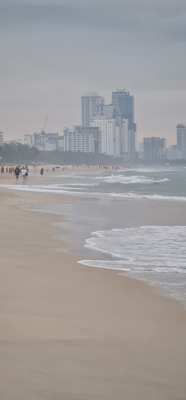 Evening beachgoers enjoy Đà Nẵng coastline under overcast skies