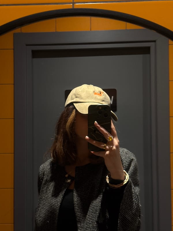 Person takes mirror selfie in Yerevan wearing hat and jewelry