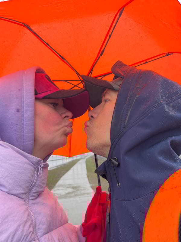 Intimate moment captured under orange umbrella in Chaikovsky rain
