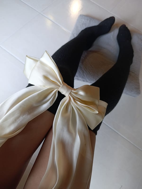 Person with white bow and black stockings documented indoors