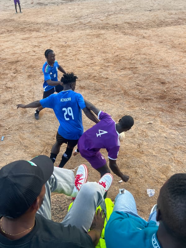 Pickup soccer match draws a crowd on a Jos dirt field