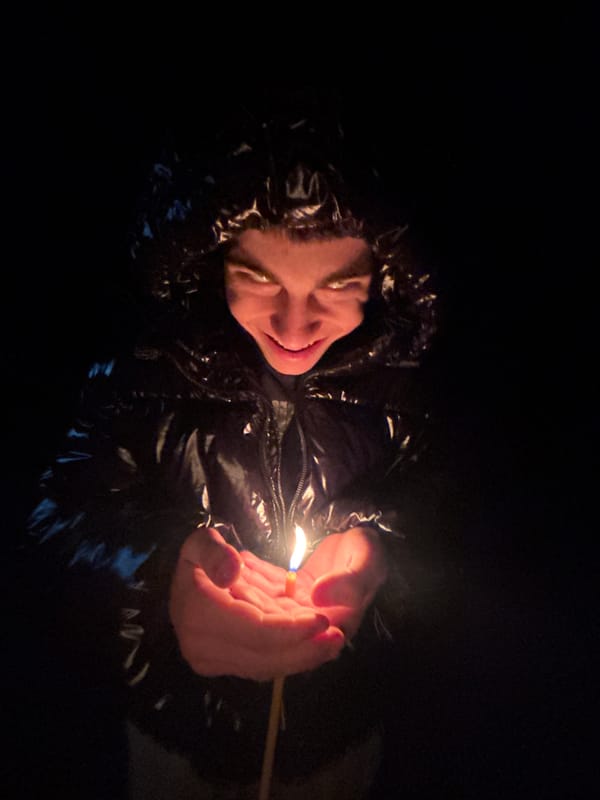 Woman holds lit match during nighttime walk in Lehchevo