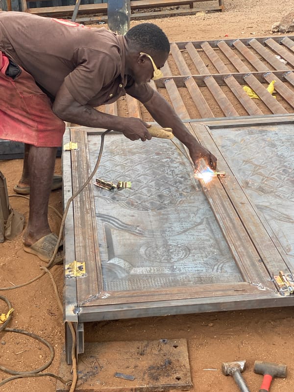 Metal workers fabricate gates in outdoor Adankolo workshop