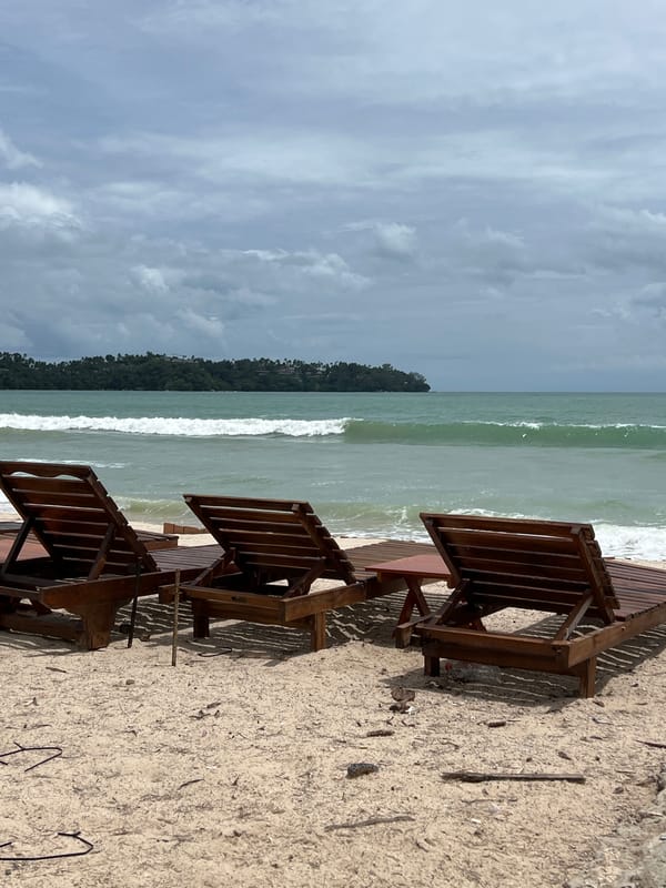 Beach scene captured with chairs, surfer, distant island