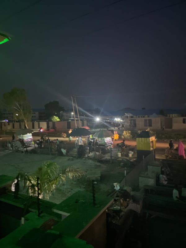 Dusk activity around a small urban compound with street food and market stalls