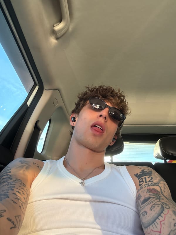 Tattooed man in white tank top observed in car