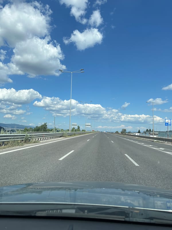 Sunny highway drive through mountainous landscape under blue skies