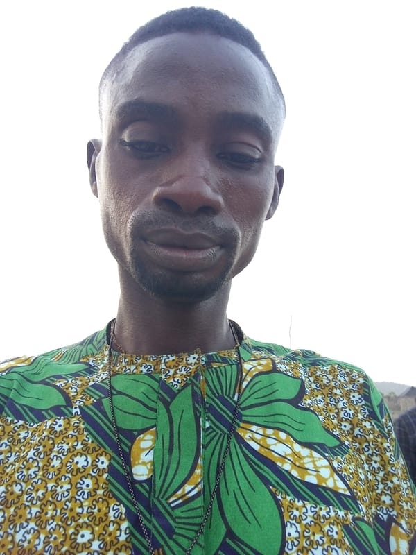 Man in patterned shirt observed looking downward outdoors