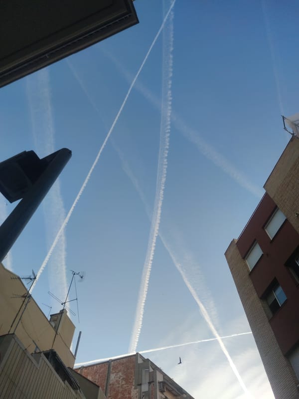 Morning contrails create crosshatch pattern over urban sky