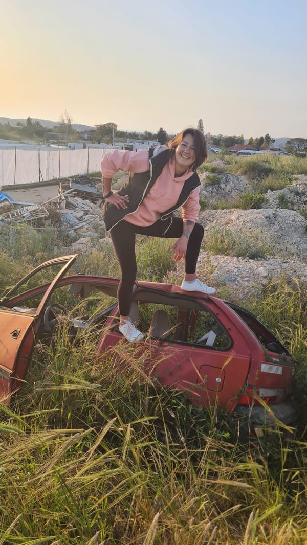 Woman poses on car wreck in Israeli countryside