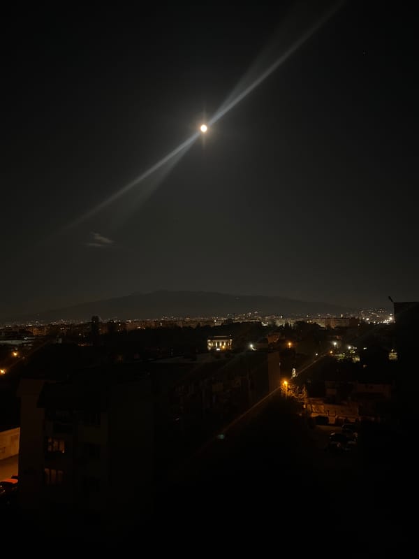 Bright moon with light beams observed over Sofia cityscape
