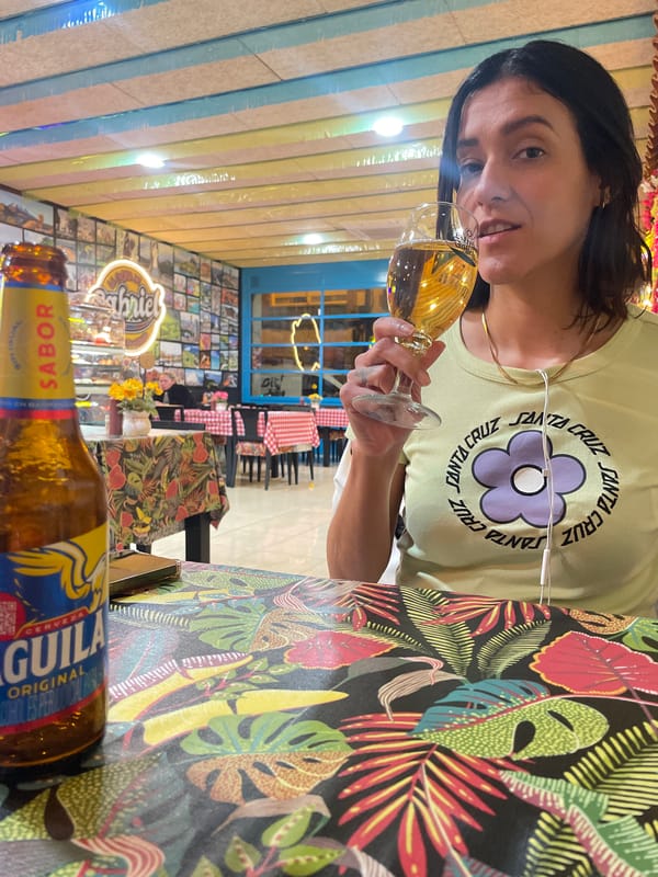 Woman enjoys Aguila beer at tropical-themed table in L'Hospitalet