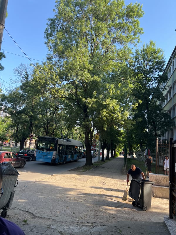 Street cleaner works as pedestrians gather on city sidewalk