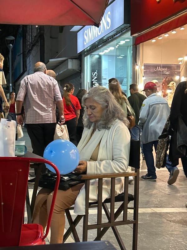 Elderly woman seated on Córdoba street late evening
