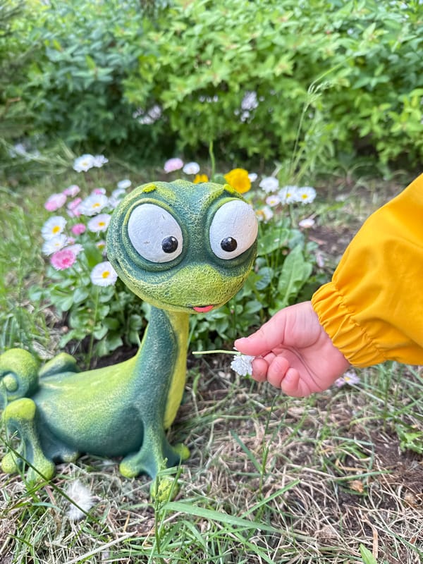 Child with flower plays near frog garden ornament in Moscow