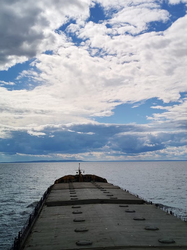 Barge crossing open water under a dramatic Russian sky
