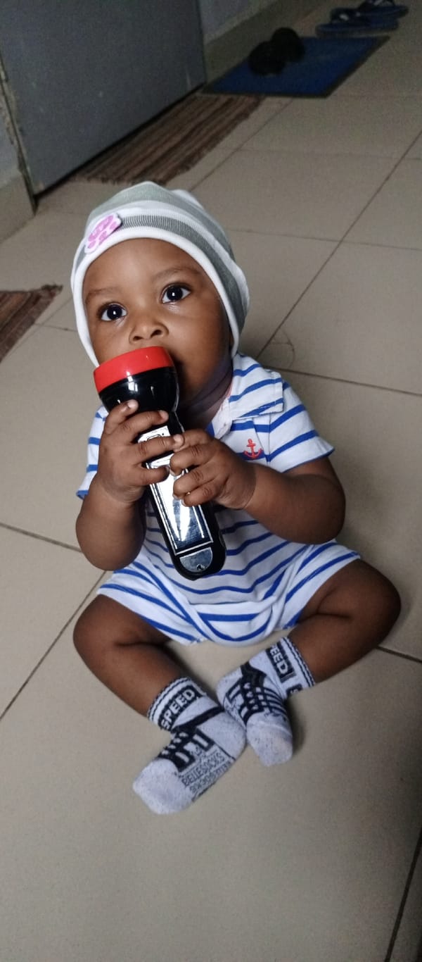Baby in striped outfit observed with flashlight across indoor locations