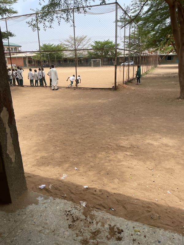 Youth play soccer on dirt field in Nigeria