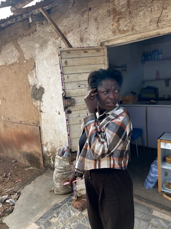 Woman makes phone call, child plays on rocks in Jos