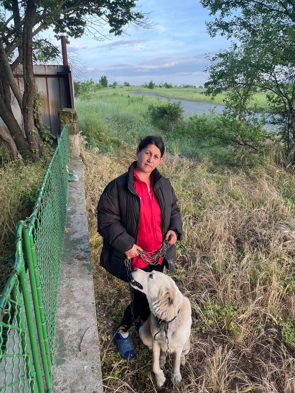 Woman sits with chained dog in rural Bulgarian village