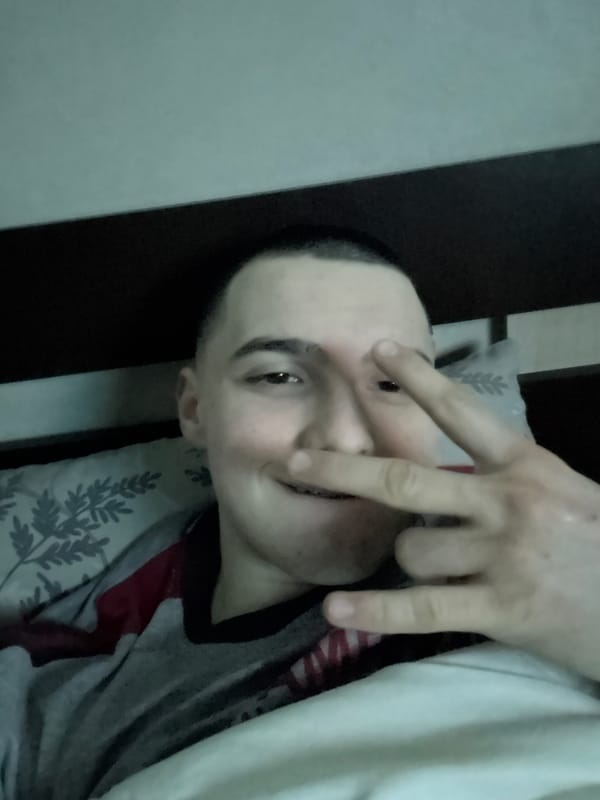Person makes peace sign while lying in bed in Sofia