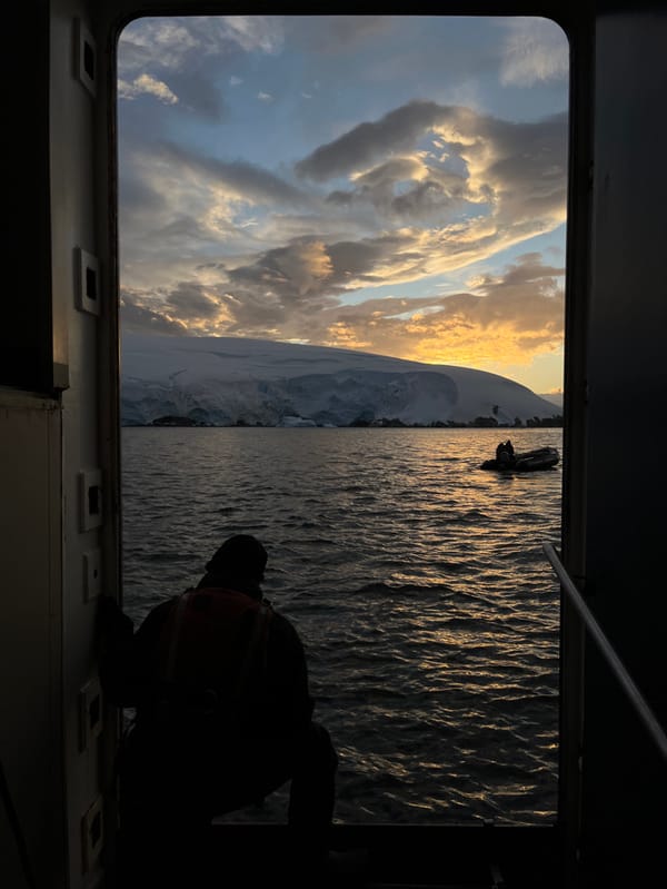 Golden sunset illuminates dramatic clouds over Antarctic mountains