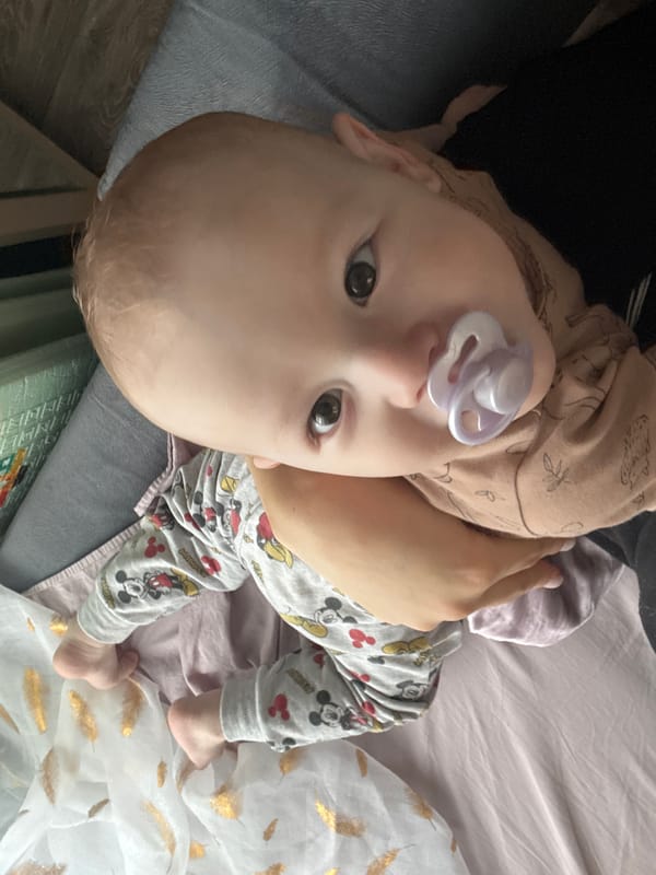 Baby in Mickey Mouse pajamas rests on decorated bed