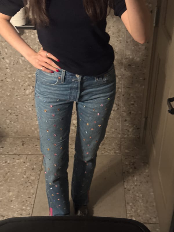 Person in embellished jeans rests on terrazzo floor in NYC