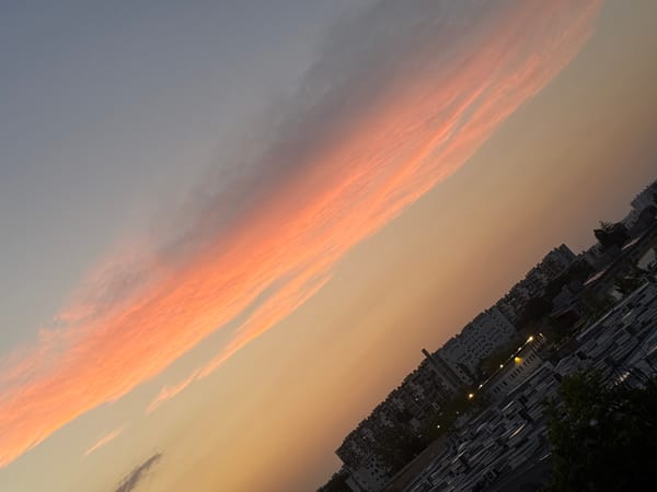 City skyline at dusk, elongated cloud lit by setting sun