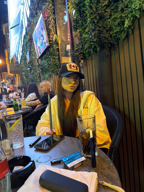 Woman in Canadian cap sits at outdoor restaurant table