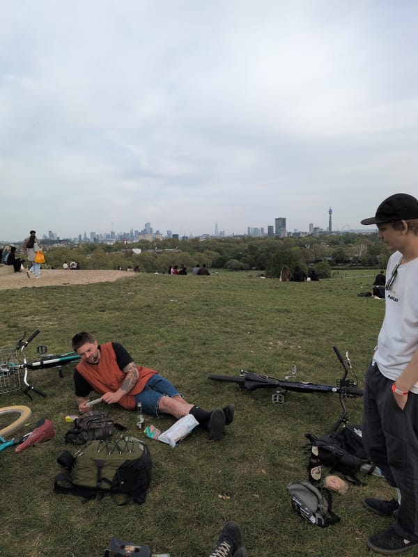 People gather on London hillside park overlooking city skyline