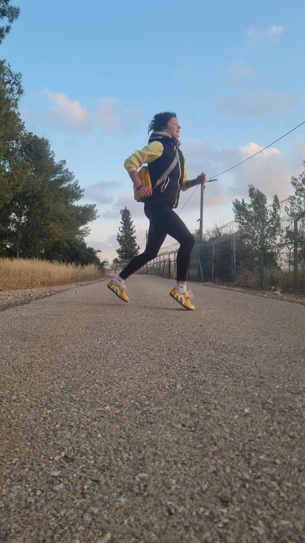 Person in yellow climbs barbed fence at sunset in Israel