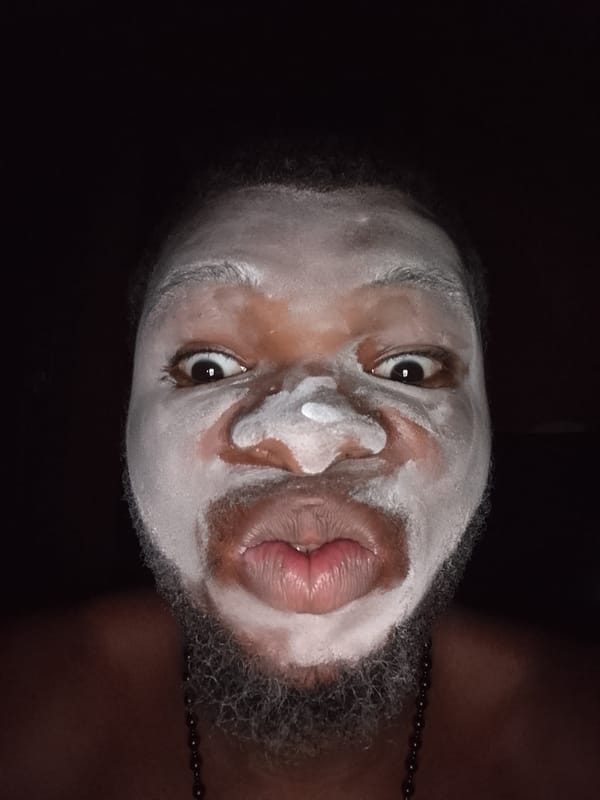Person photographed in white theatrical face paint during evening hours