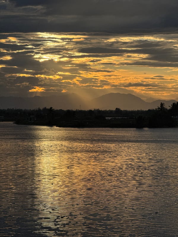 Golden hour light over a calm river in Hoi An