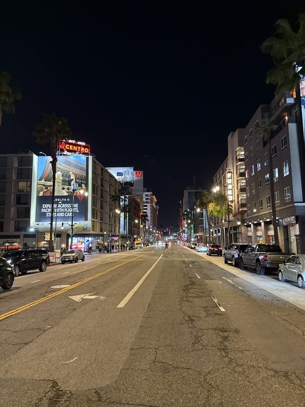 Empty LA street observed at dawn with neon-lit buildings