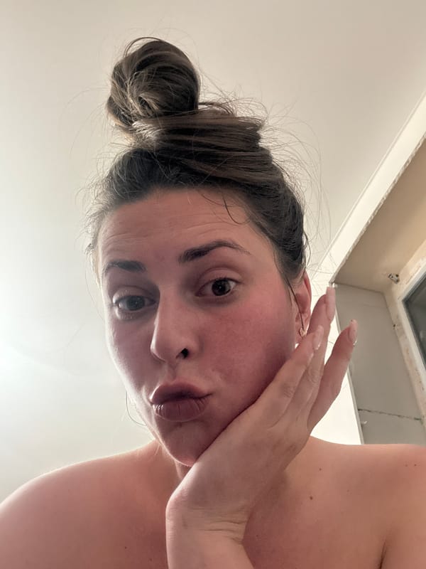Woman takes selfie pose indoors with hand on cheek