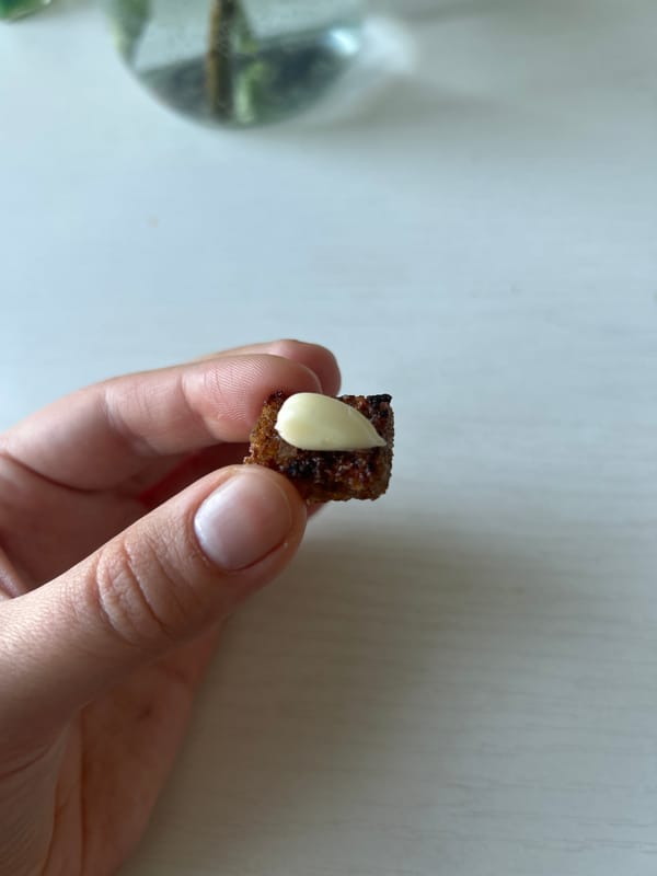 Person holds crouton with white spread at unknown location