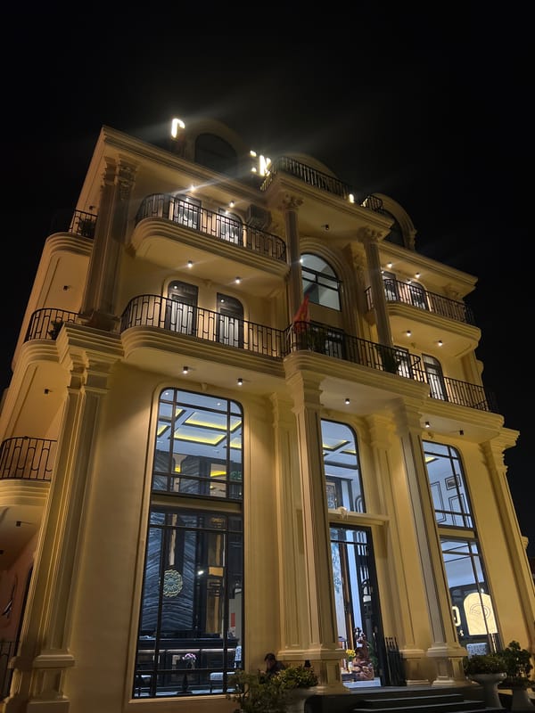 Illuminated yellow building photographed at night in Da Lat