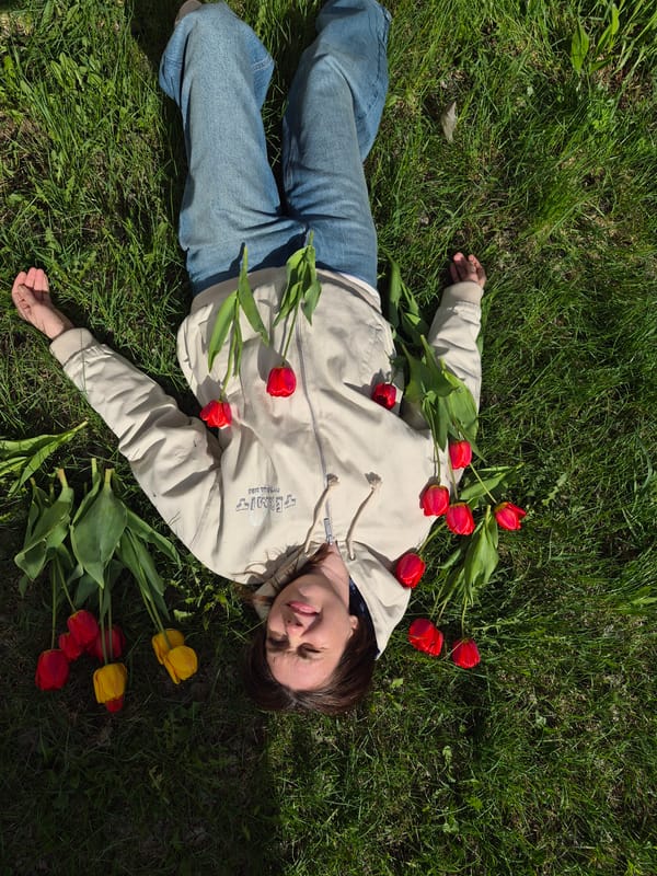 Woman poses with tulips in grass in Chaikovsky