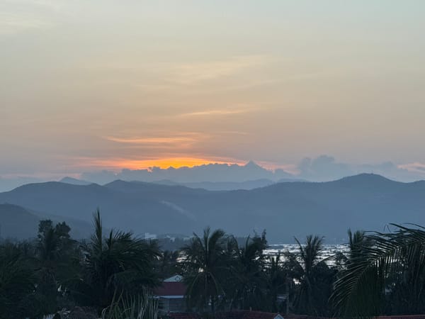 Sunset over Song Cau's coastline, palms and mountains in silhouette