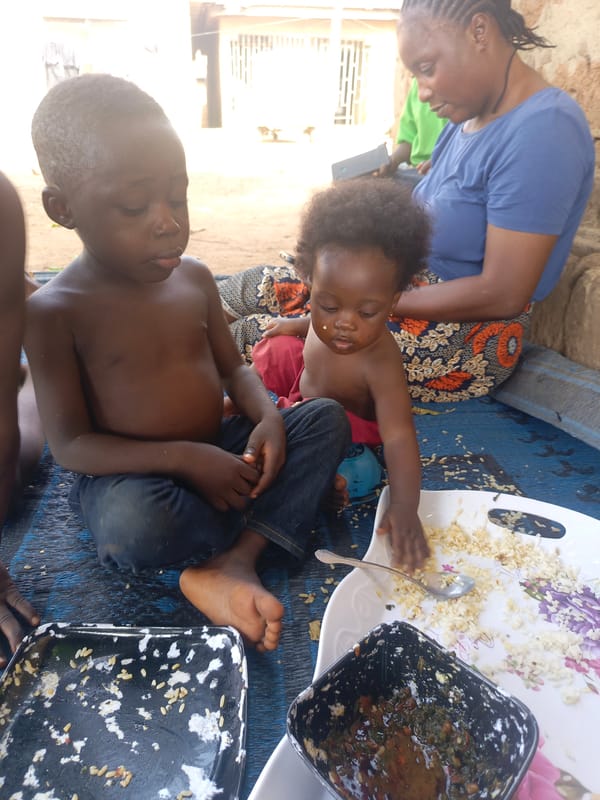 Woman supervises children's outdoor meal on blue mat