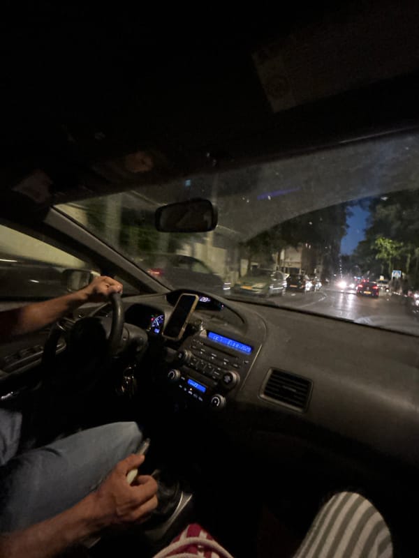 Nighttime drive through Rishon LeZion, hand on the wheel.