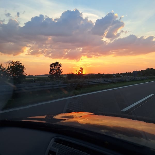 Sunset highway drive, sky blazing through the windshield